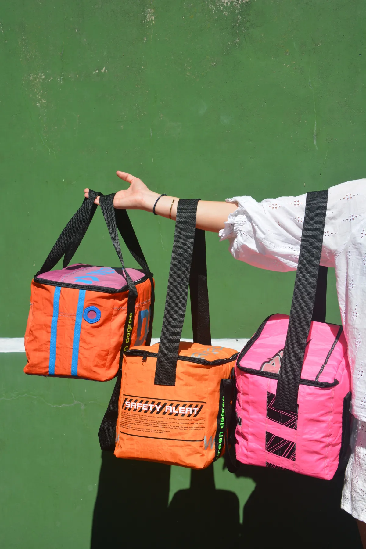 three kite-fabric cooler bags in orange, pink and blue