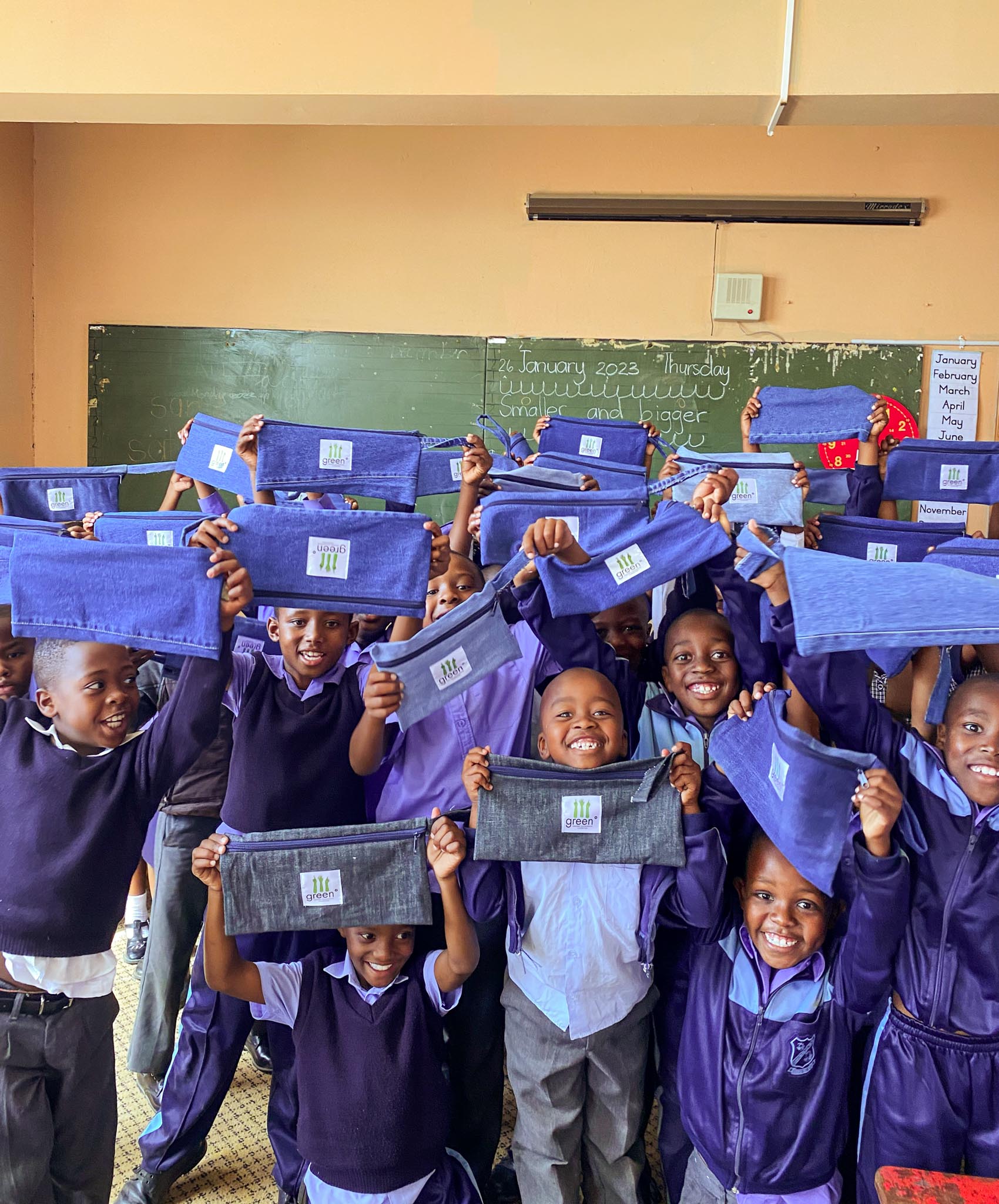 children at capricorn primary holding up green° denim pencil cases